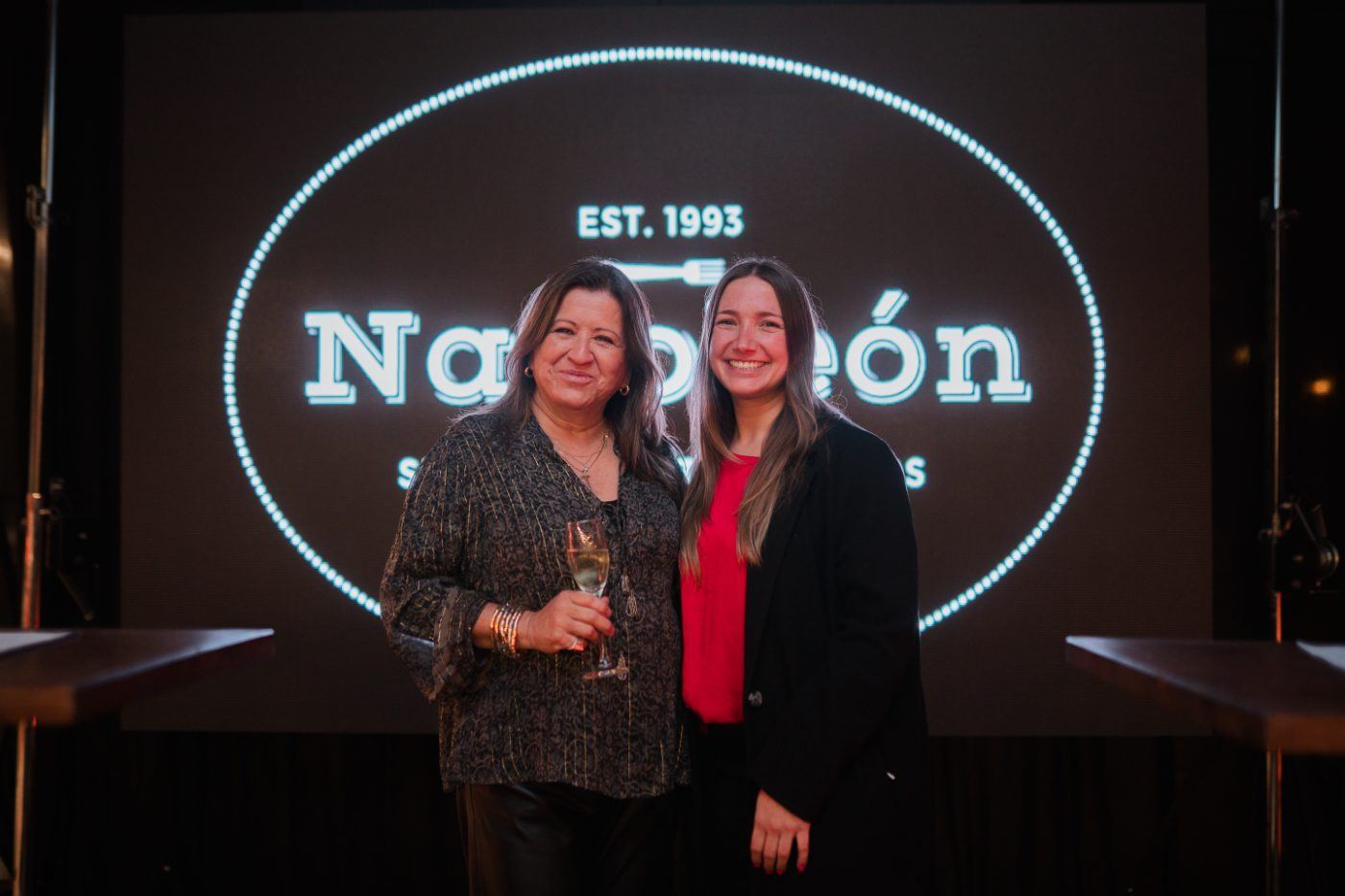 Invitadas frente al logo Napoleón